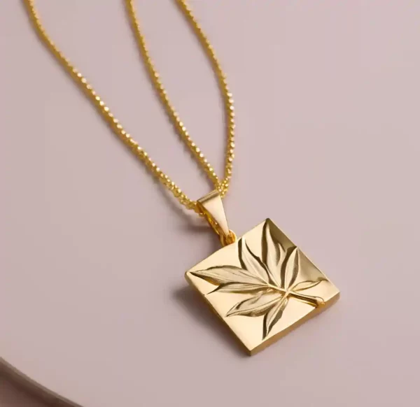 Pendentif de løv en or composé d'une chaine et d'un carré sculptée d'une feuille par l'artiste Méta.