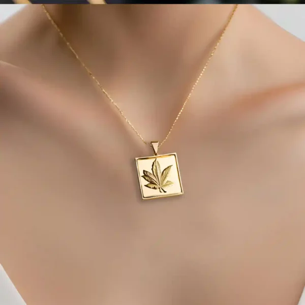 Pendentif de løv en or composé d'une chaine et d'un carré sculptée d'une feuille par l'artiste Méta.