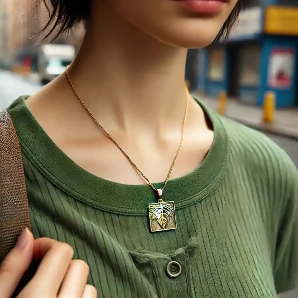 Femme portant le pendentif de løv en or composé d'une chaine et d'un carré sculptée d'une feuille par l'artiste Méta